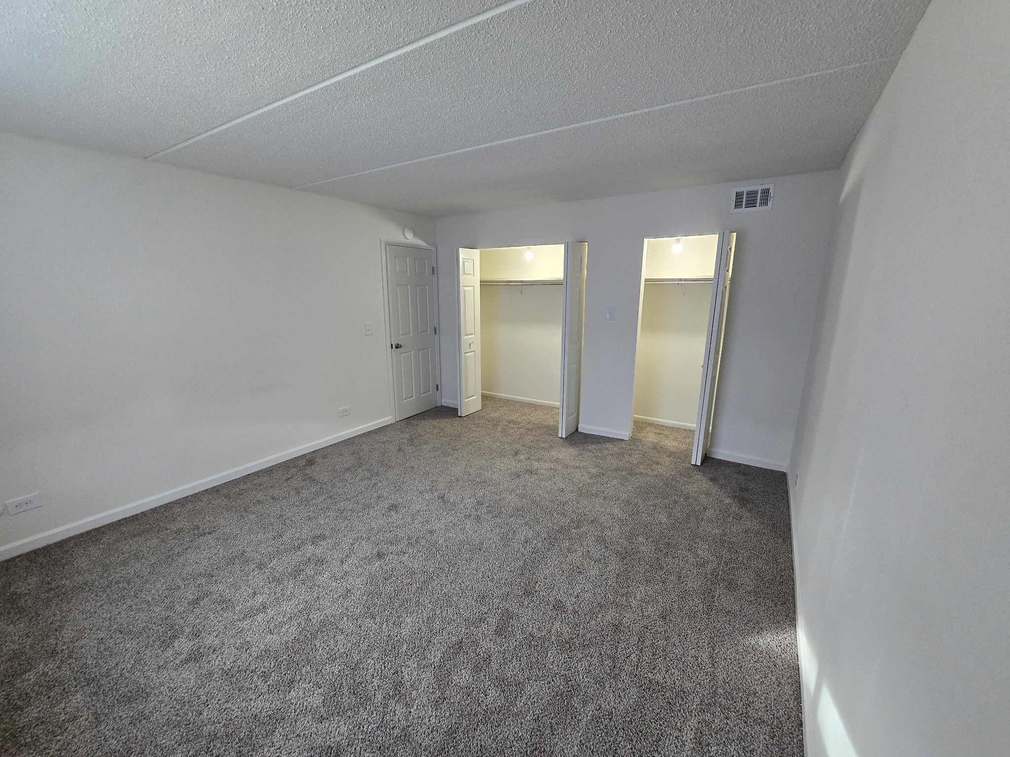 A sparsely furnished room with a carpeted floor and white walls.